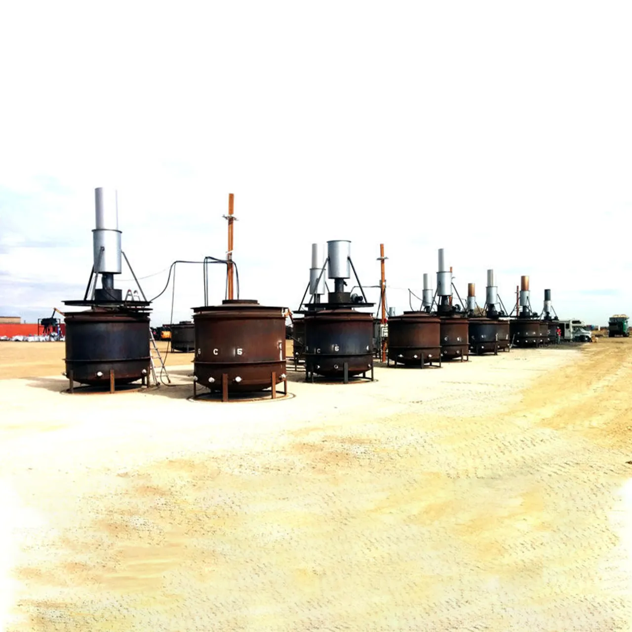 A row of portable biochar kilns